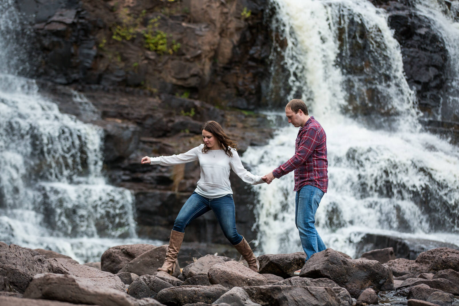 Gooseberry Falls Engagement Session couple leaping on river rocks