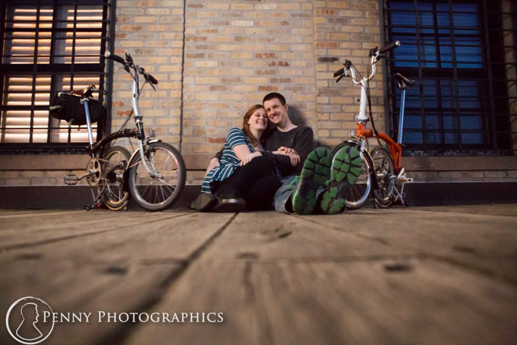 Bicycle Engagement couple with bicycles against brick wall