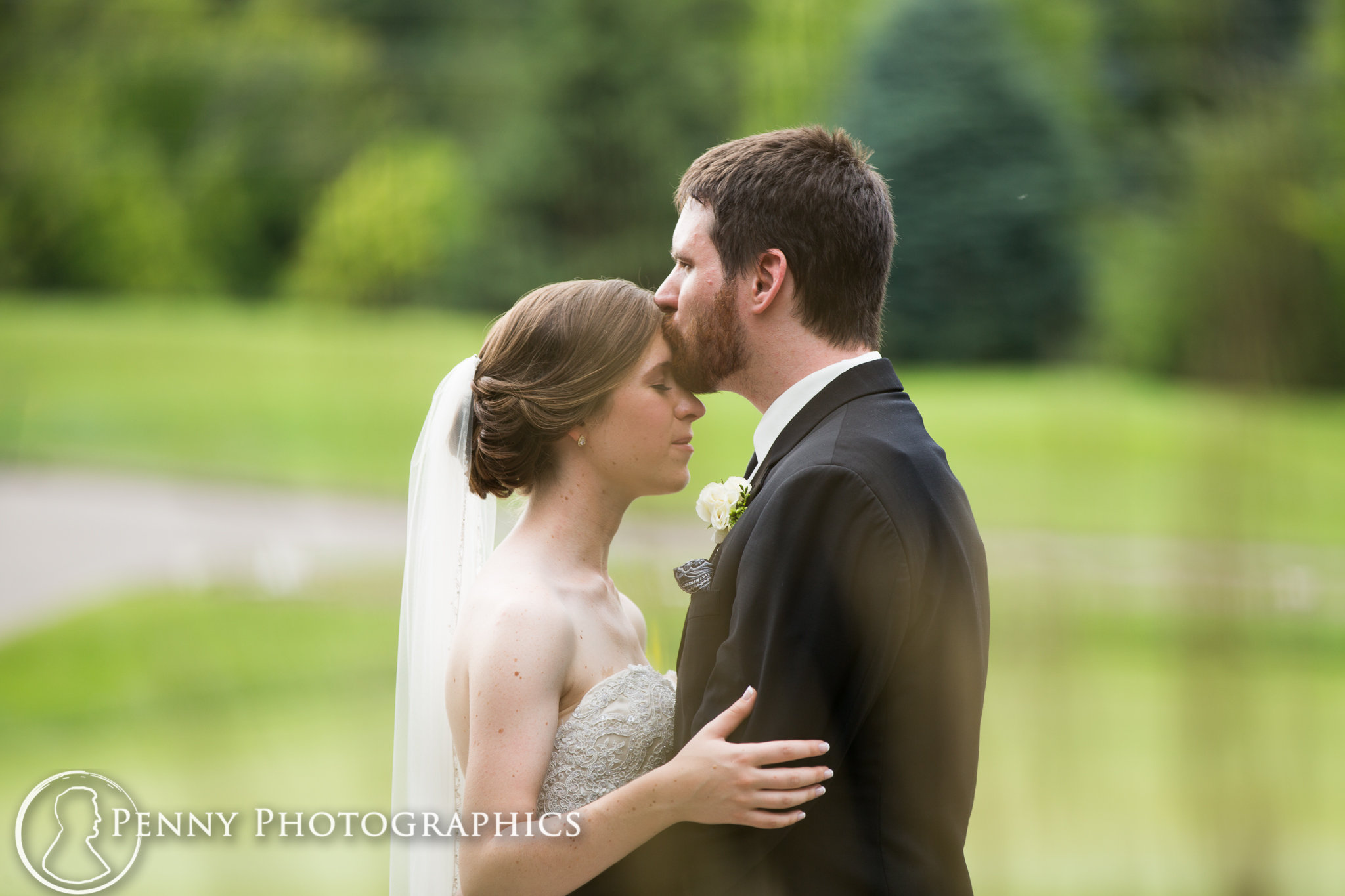 Groom kissing bride on forehead