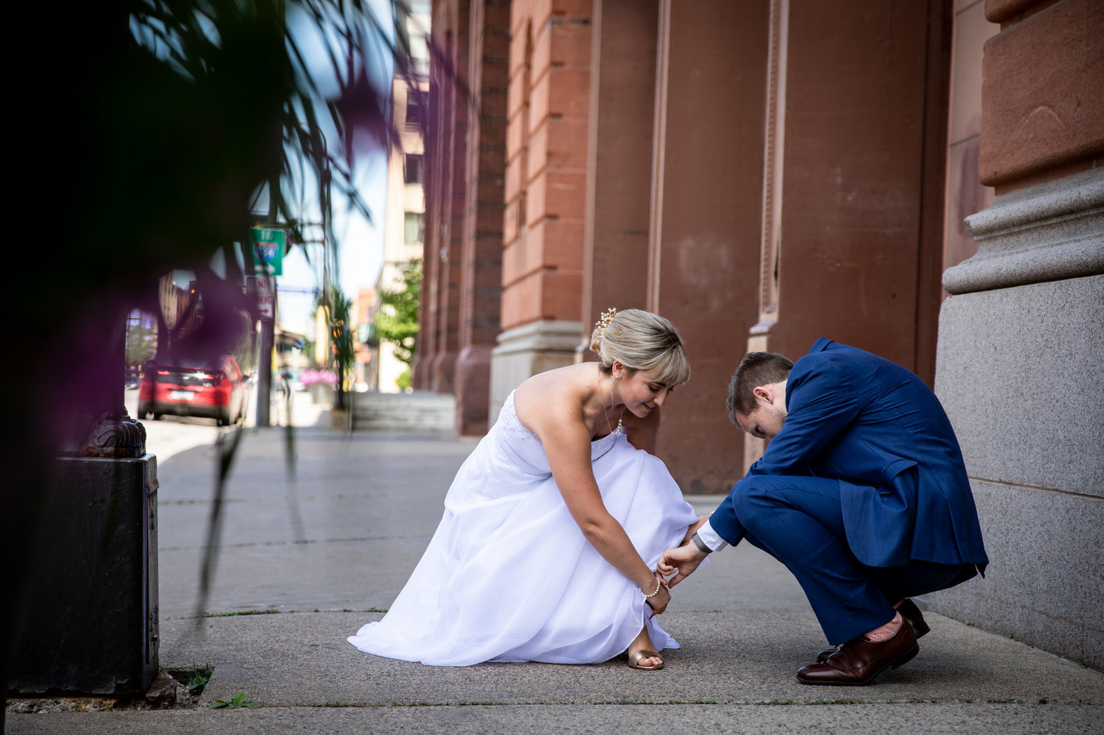 Groom helping bride with shoe at Watson Block Wedding
