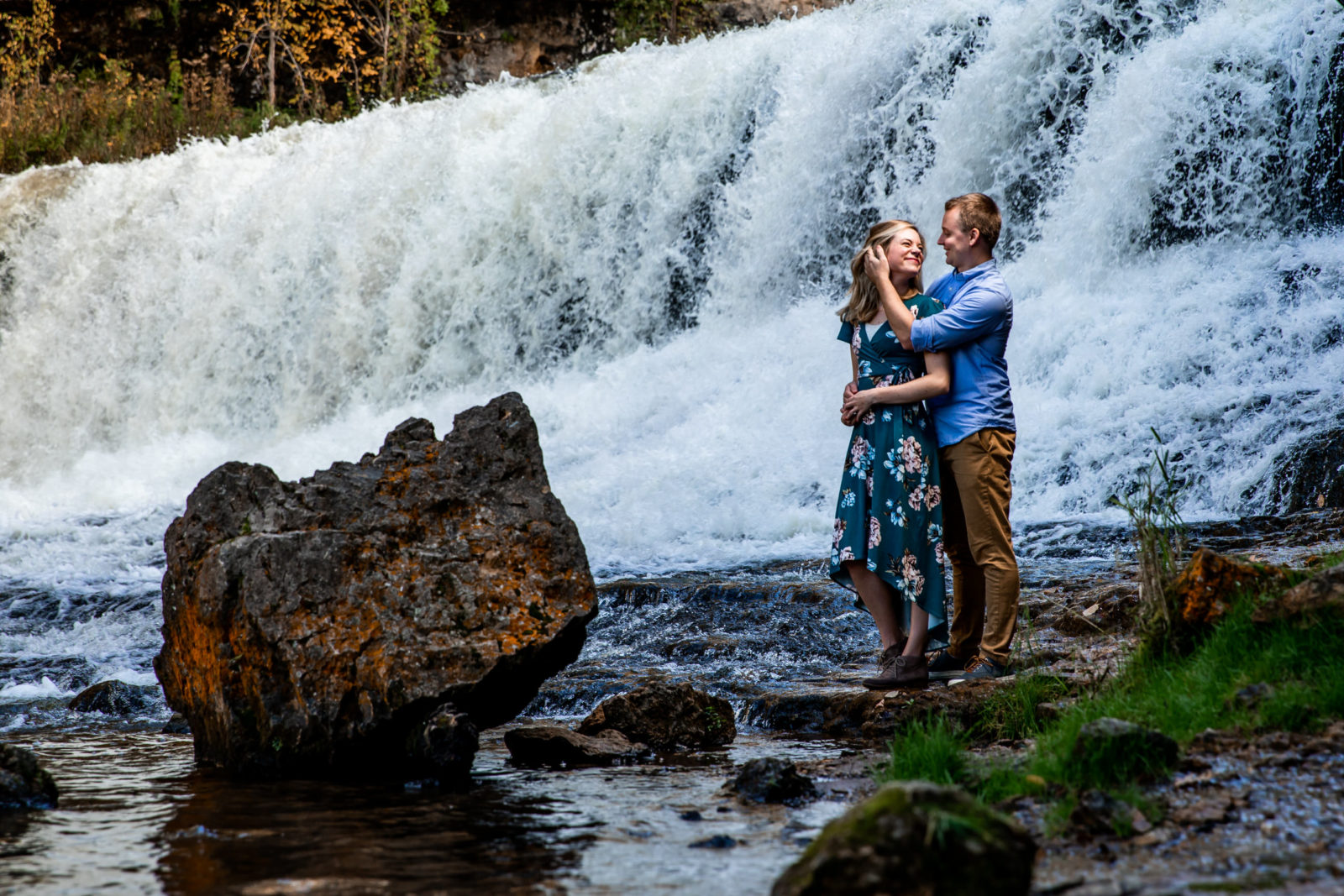 couple in front of waterfall fall engagement