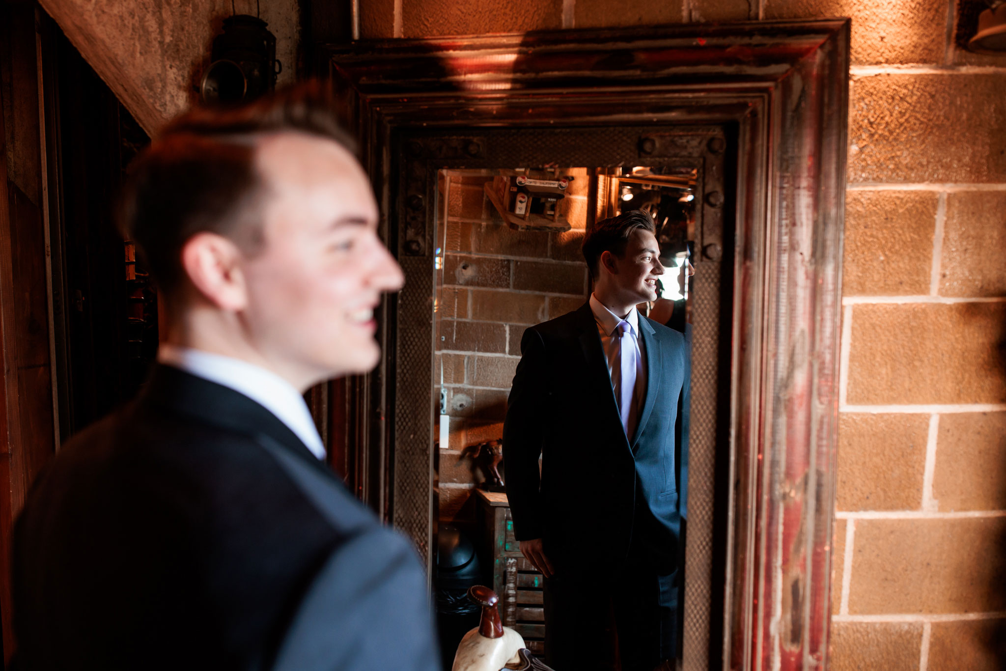 Groom's portrait in a mirror reflection looking out the window.