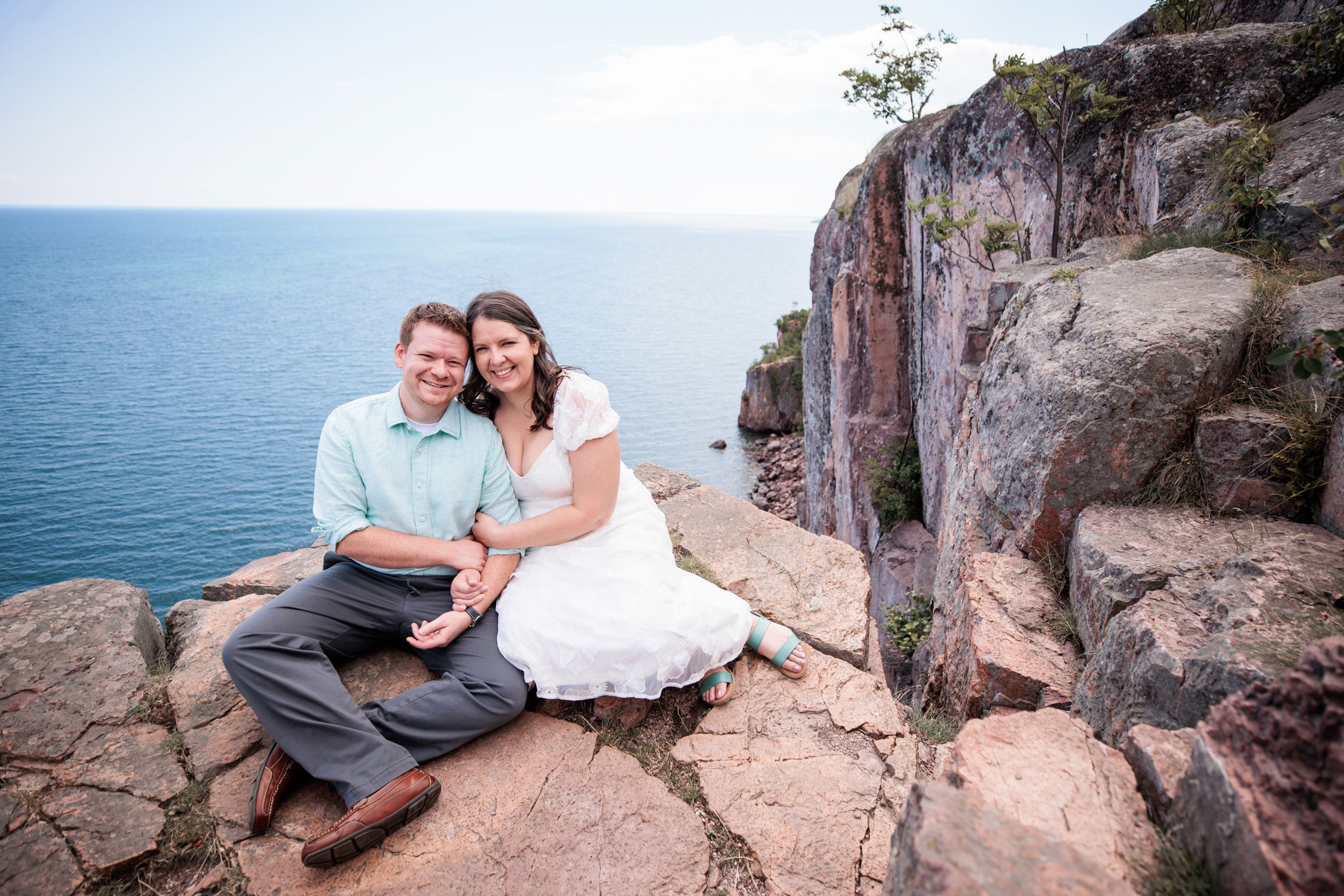 Engaged couple sitting on a rock on Palisade head in Two Harbors, MN.