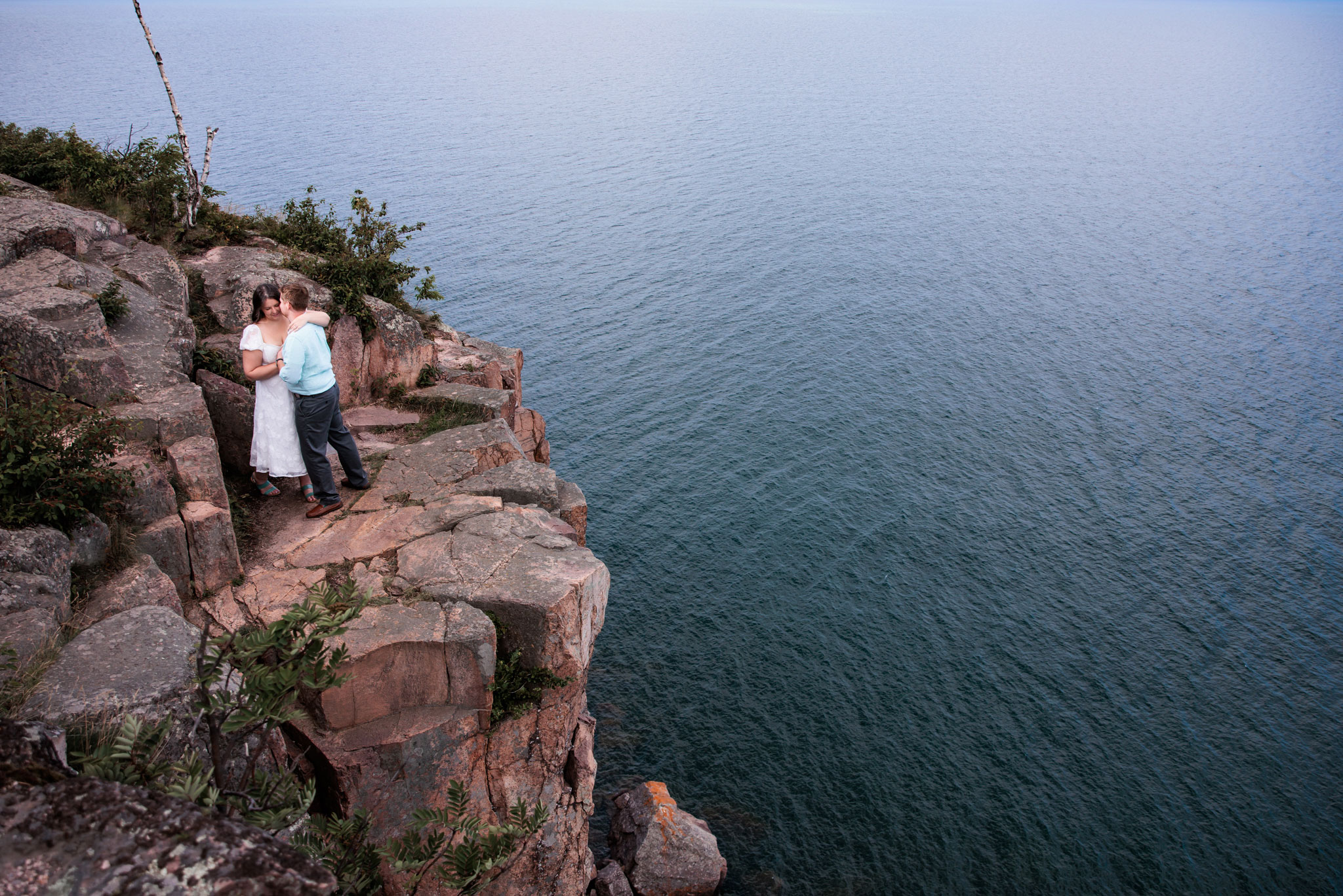 Birds eye view of a couple embracing on a rock on Palisade head in Two Harbors, MN.