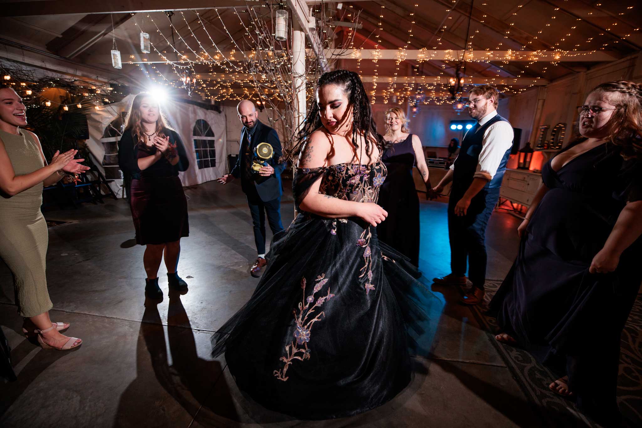 A bride in balck wedding dress spinning on the dance floor at Camrose hill wedding venue.