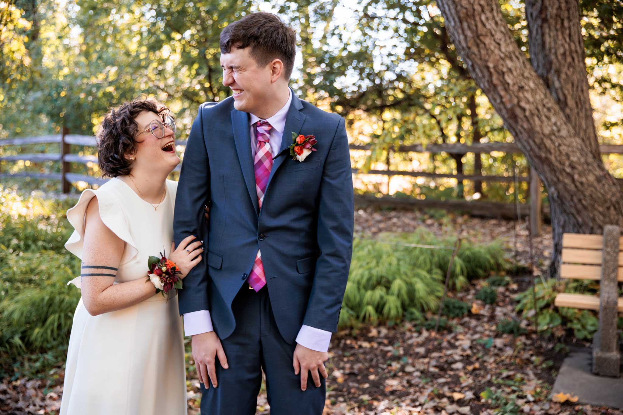A fun photo of a bride sneaking up on her groom outside in the Lyndale peace garden in Minneapolis.