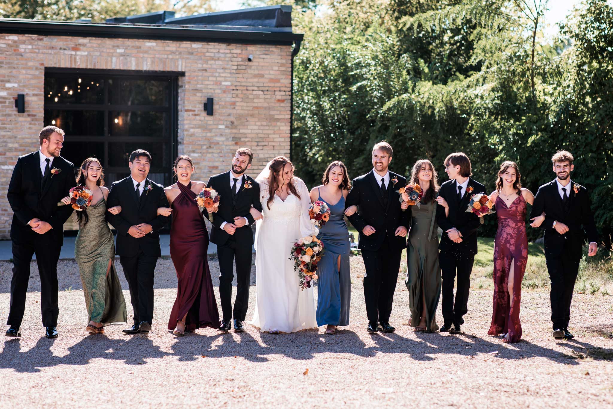 Wedding party in single file walking outside of the Mill site wedding venue in Anoka.