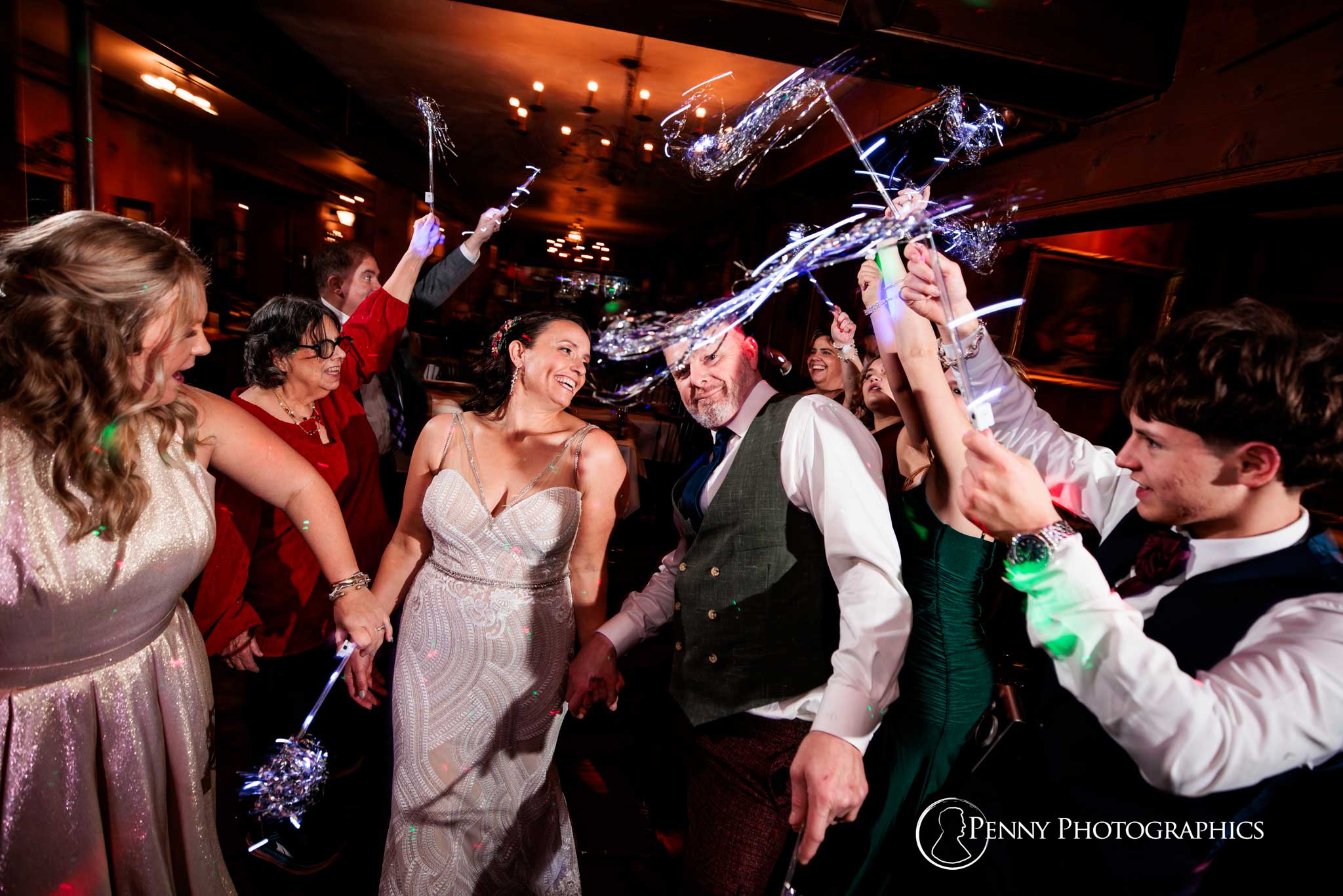 A bride and groom walking through a line of tinsel wants during wedding reception.