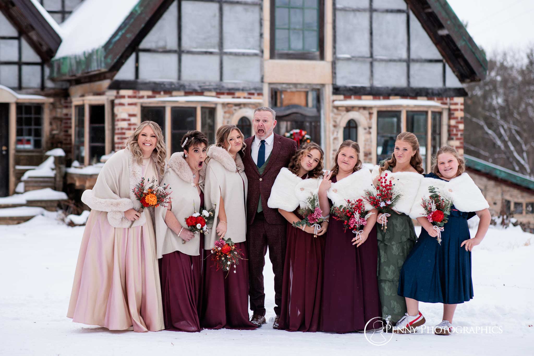 A wedding party portrait outside of a house in the snow.